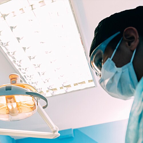  Young female technician looking into microscope in medical laboratory