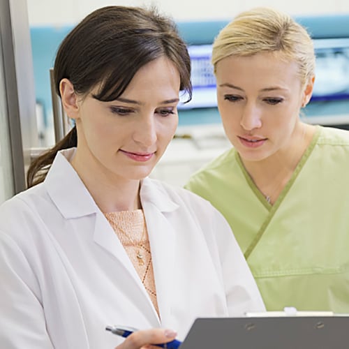 Young female technician looking into microscope in medical laboratory Young female technician looking into microscope in medical laboratory